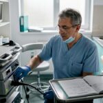 Un medic reglează aparatul de endoscopie înaintea unei investigații, în cabinetul clinicii.