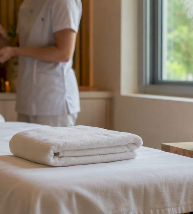 Masă de masaj amenajată într-un spațiu de clinică, cu o atmosferă liniștită și relaxantă.