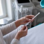 Mâinile unei femei țin un aplicator pentru tratament vaginal.