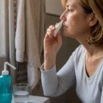 Femeie care folosește un spray nazal cu corticosteroizi